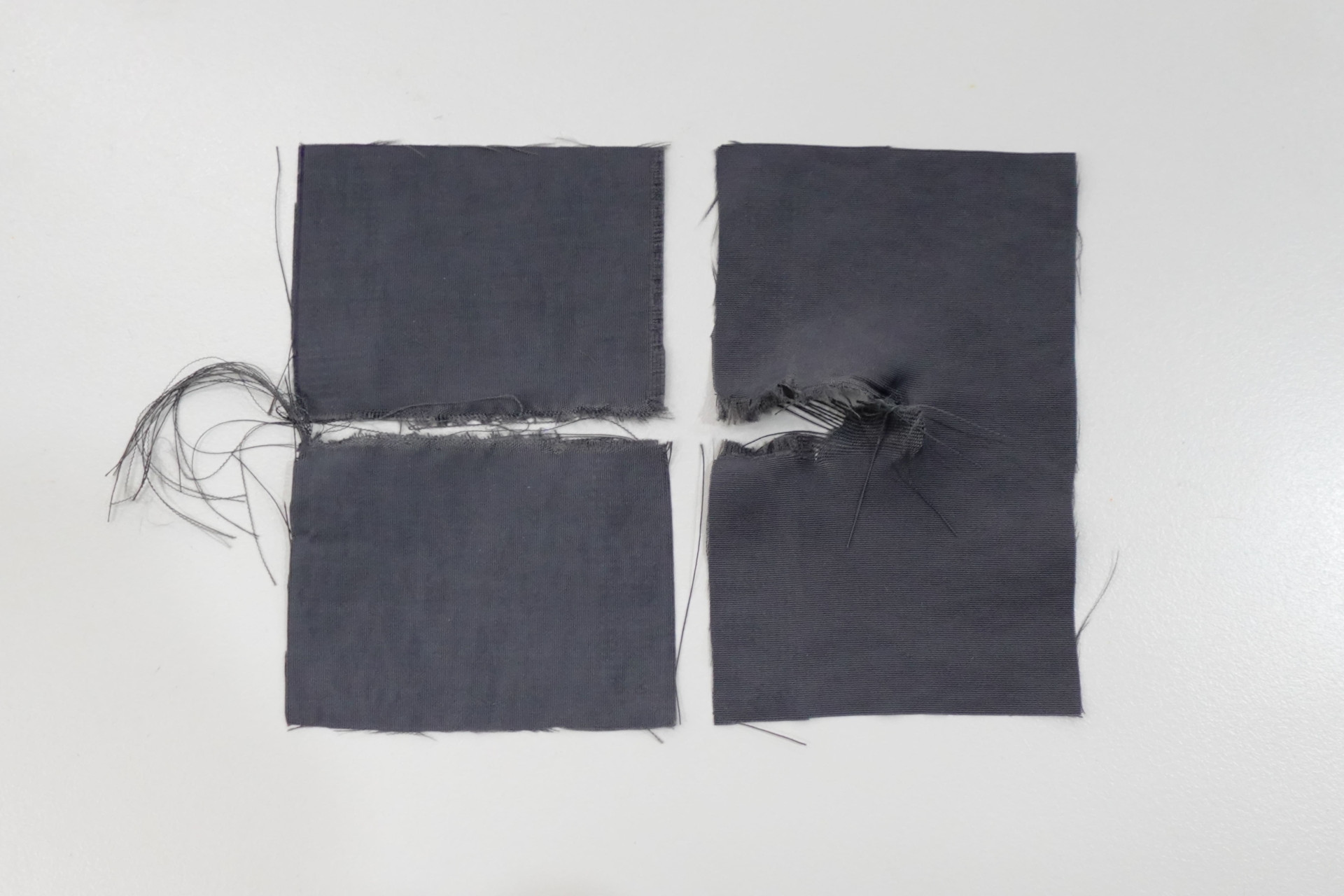 Fabric tear test samples after testing, showing torn fabric with frayed edges