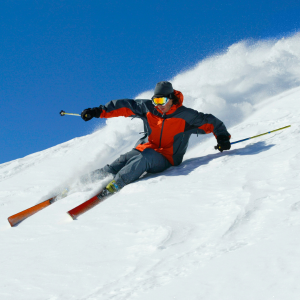 Skier wearing waterproof and breathable functional fabric apparel in motion on snowy slopes